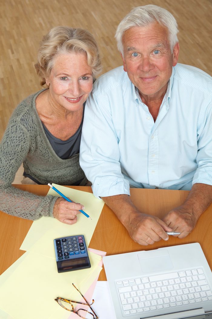 Happy senior couple using a laptop and calculator for financial planning.